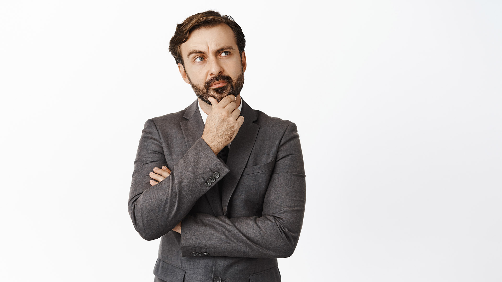 Thoughtful boss in suit looking up, touching his beard while thinking, pondering new ideas, searching solution, making choice, white background