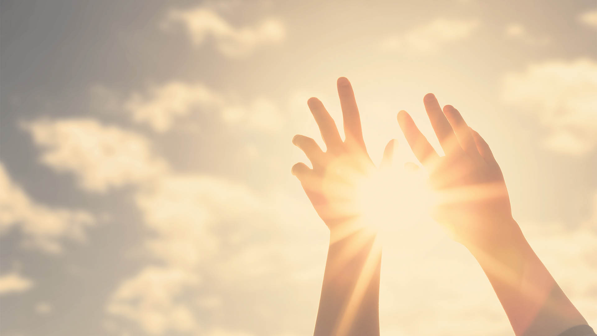 Woman hands reaches for the sky and closes the sun, the sun's rays pass through the hand