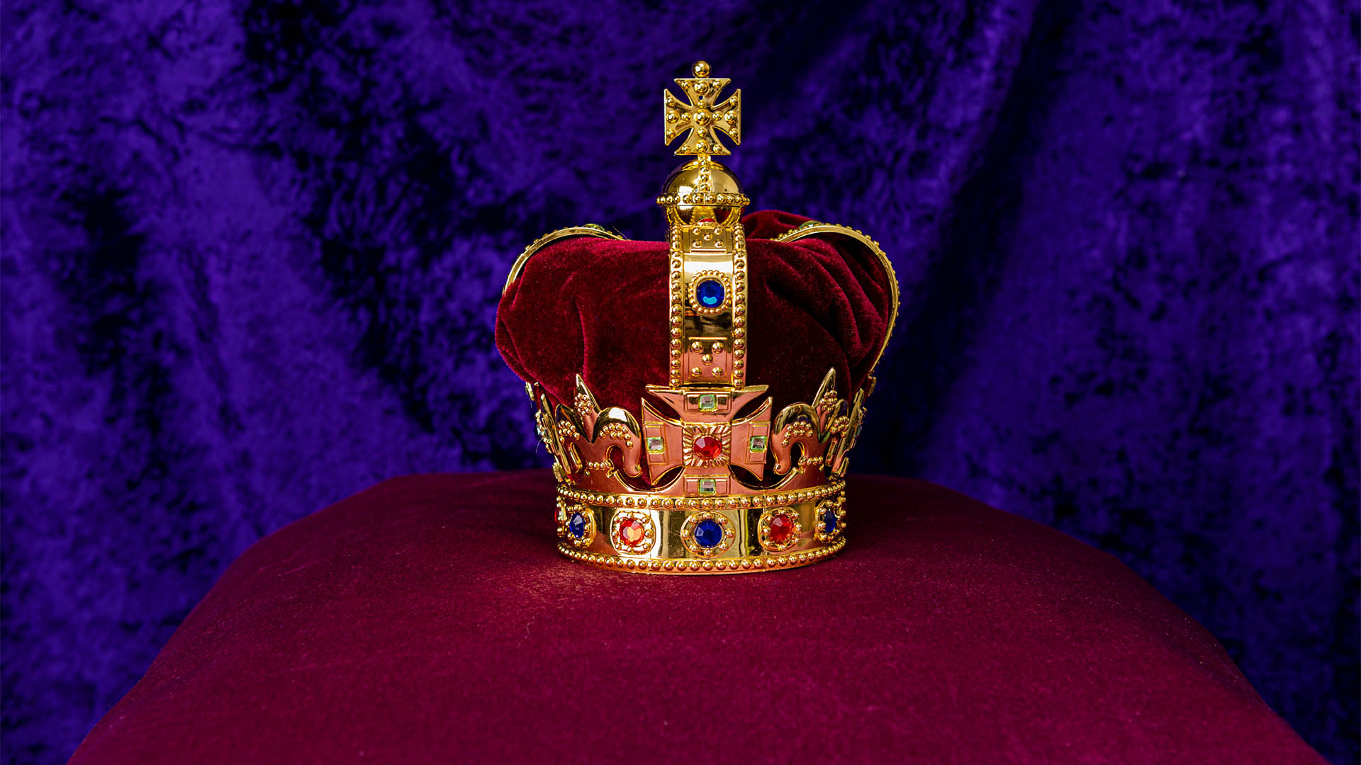 King Edwards Crown to be used by King Charles III for his Coronation sits on a purple pillow with a purple background.