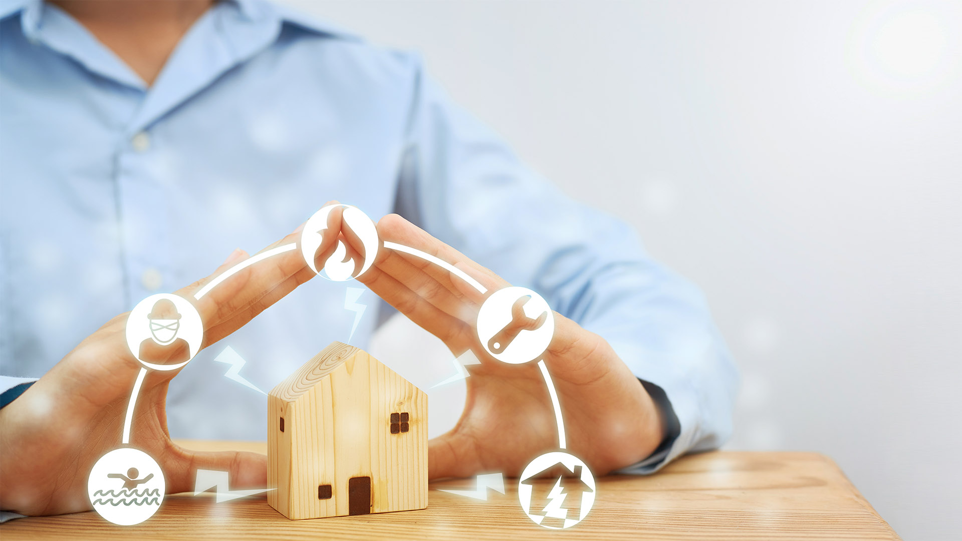 Female hands showing gestures protect a model wooden house. Residential care ideas. Concept of home protection and insurance against natural disasters and theft.