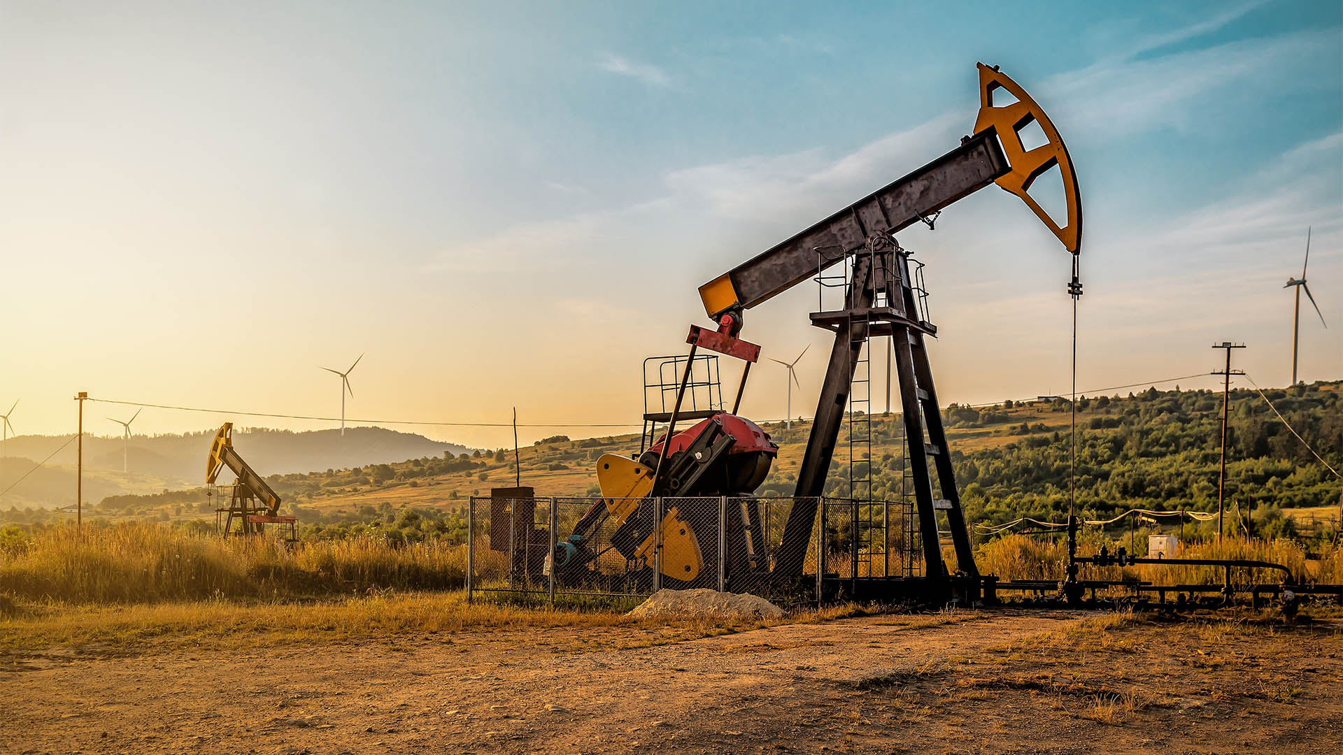 Industrial working oil pump on crude oil field at sunset