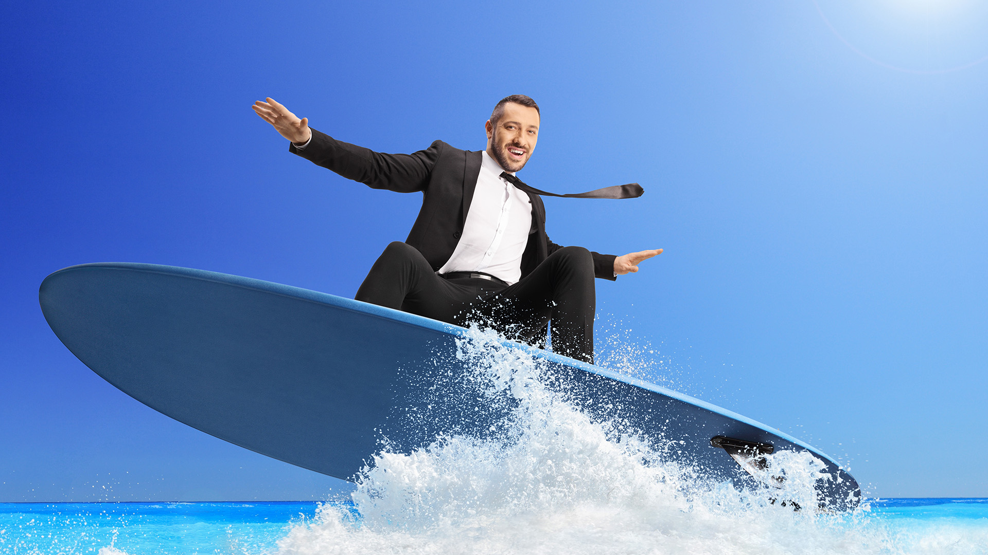 Businessman riding a surfboard on a sea wave