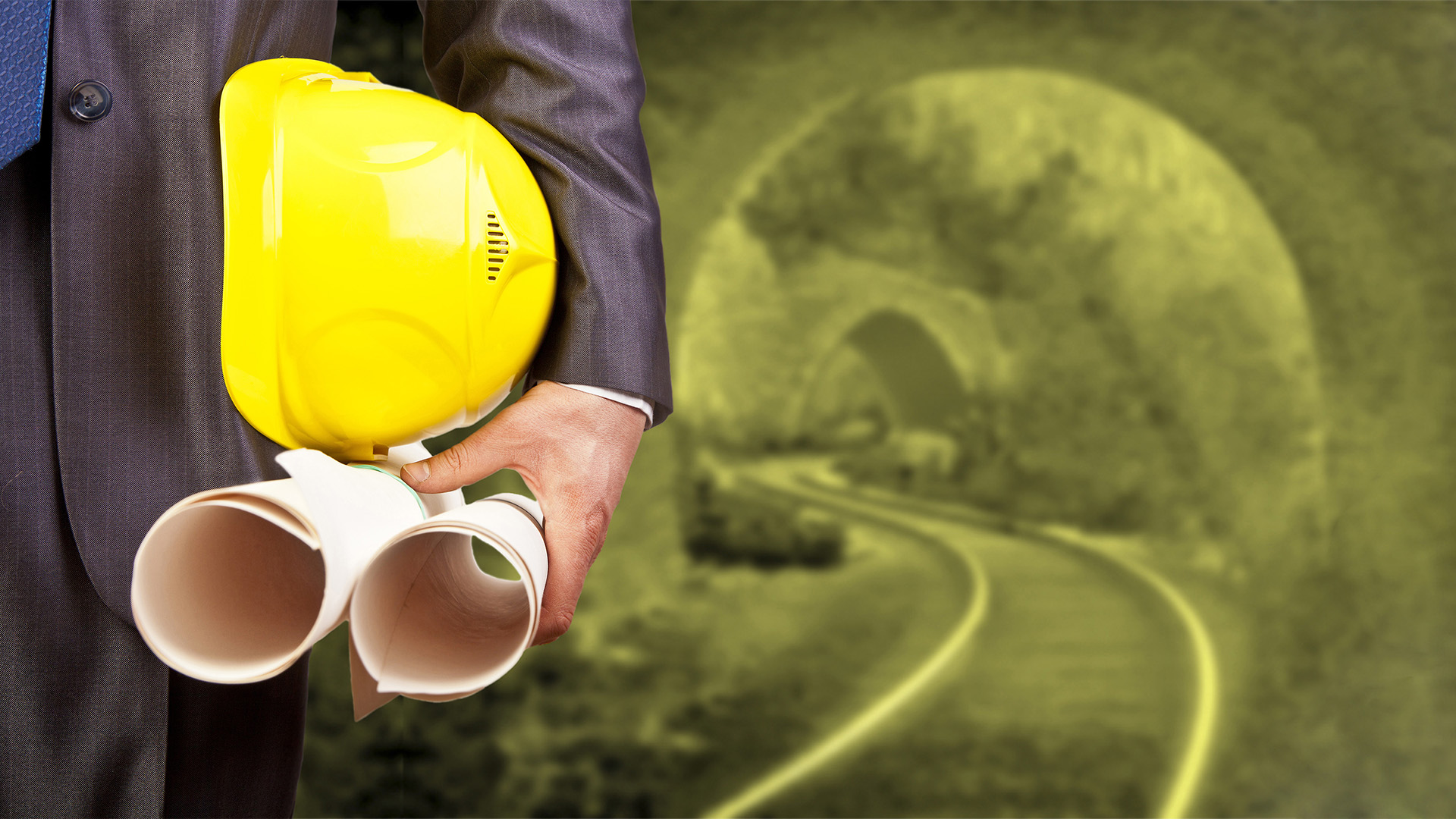 engineer or worker holding in hand helmet for workers security and blueprint paper plan on background of an underground mine with arc legs and rails for trolleys with coal in perspective Copy space