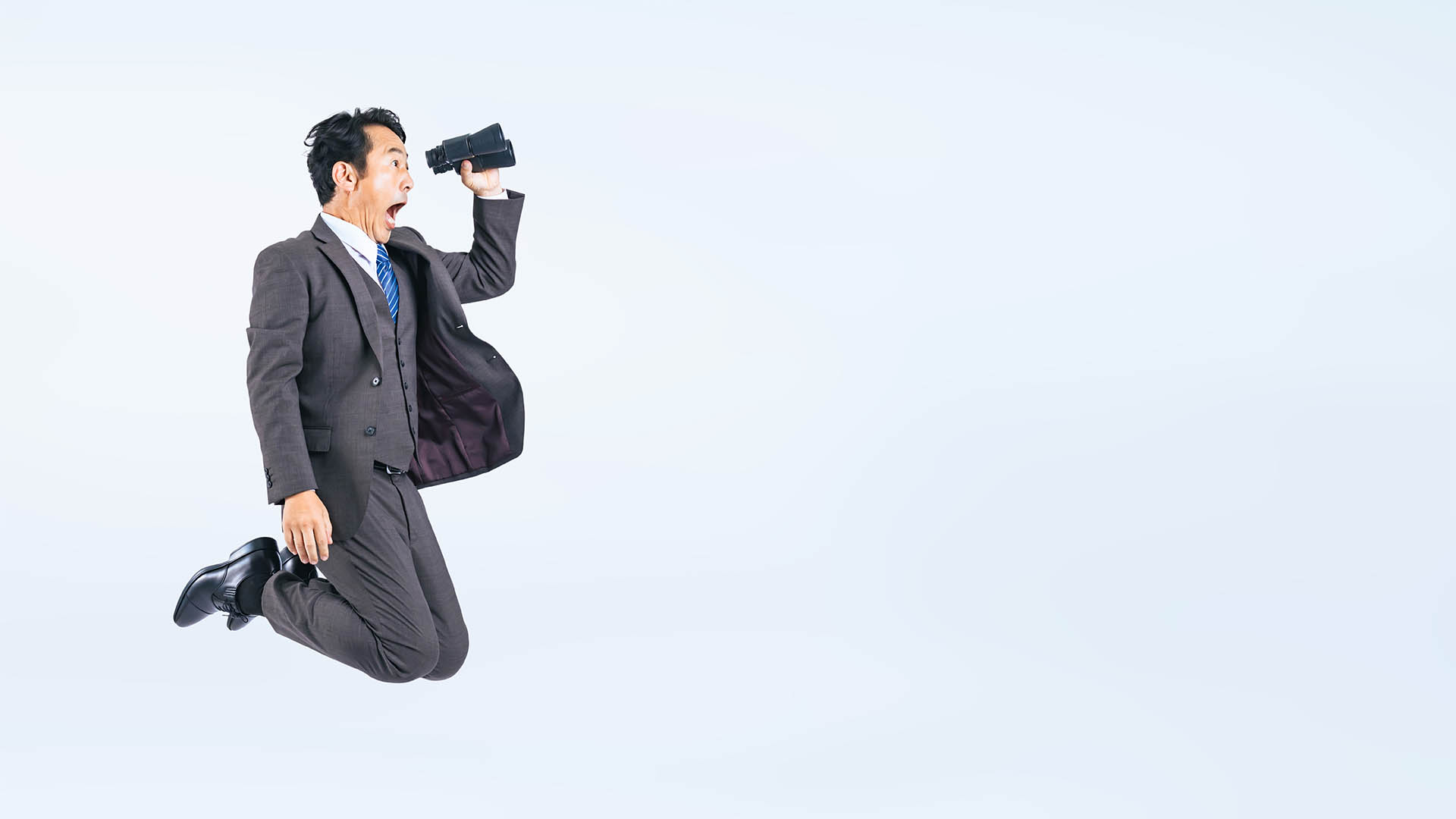 Jumping Middle aged Asian businessman with binoculars.