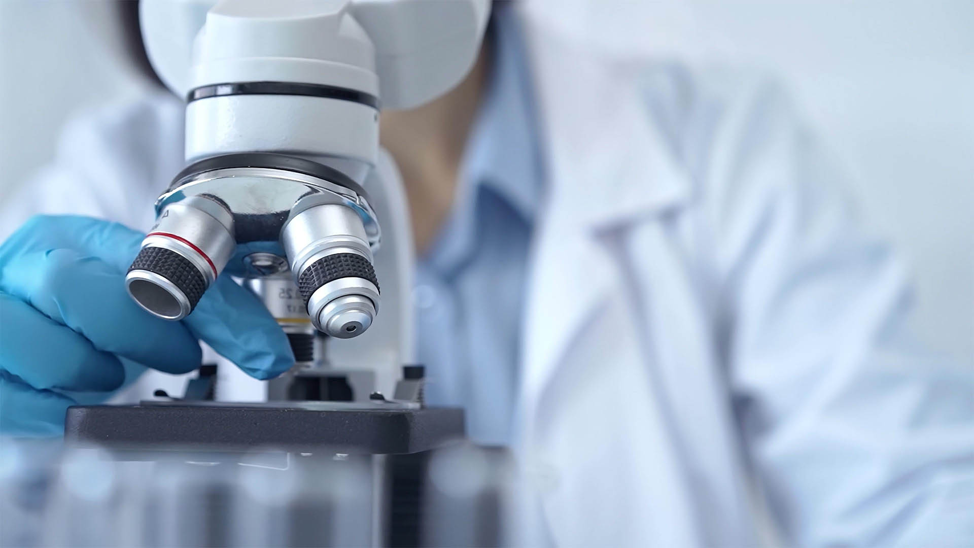 Scientist using microscope in laboratory. Close-up of a researcher's hands adjusting a modern microscope in a lab setting. Science concept