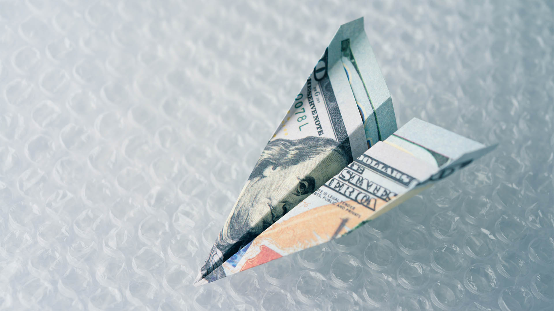 Soft landing in economic concept. US banknotes plane soft landing fall on air bubble sheet. FED central bank control interest rates and other monetary policy for suitable growth and fix economy crisis