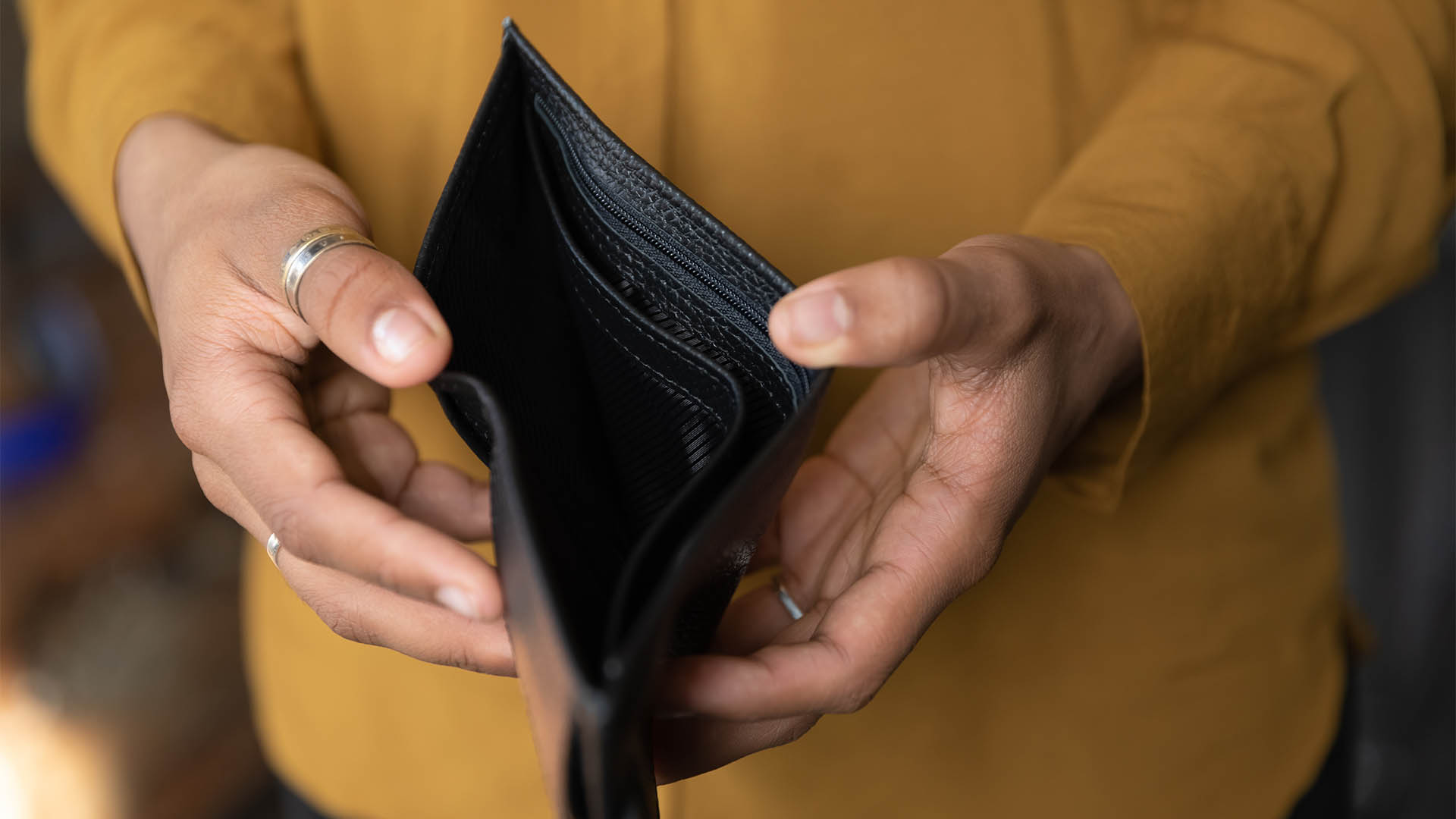 Close up young African American unemployed woman holding opened empty black leather wallet. feeling stressed without cash, having financial problems, suffering from lack of money, bankruptcy concept.