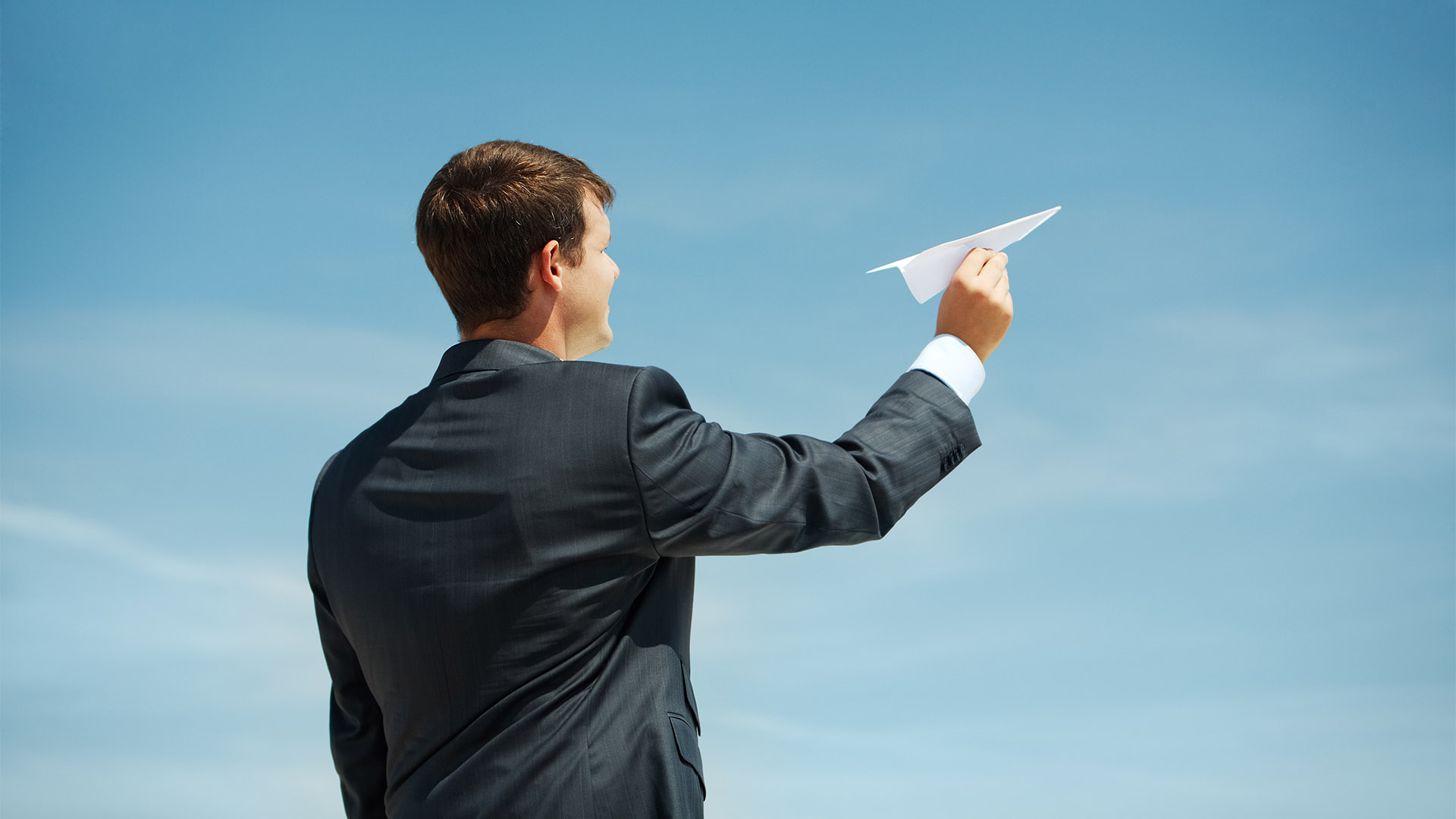 Photo of businessman holding paper aircraft in stretched hand before launching it