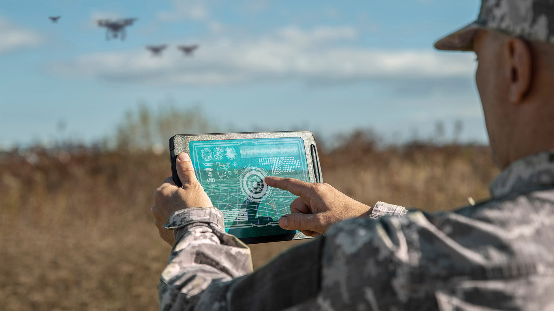 Army technologies. Warfare analytic operator checking coordination of the military team with drones. Military commander with a digital tablet device with augmented reality operating troops outdoors.