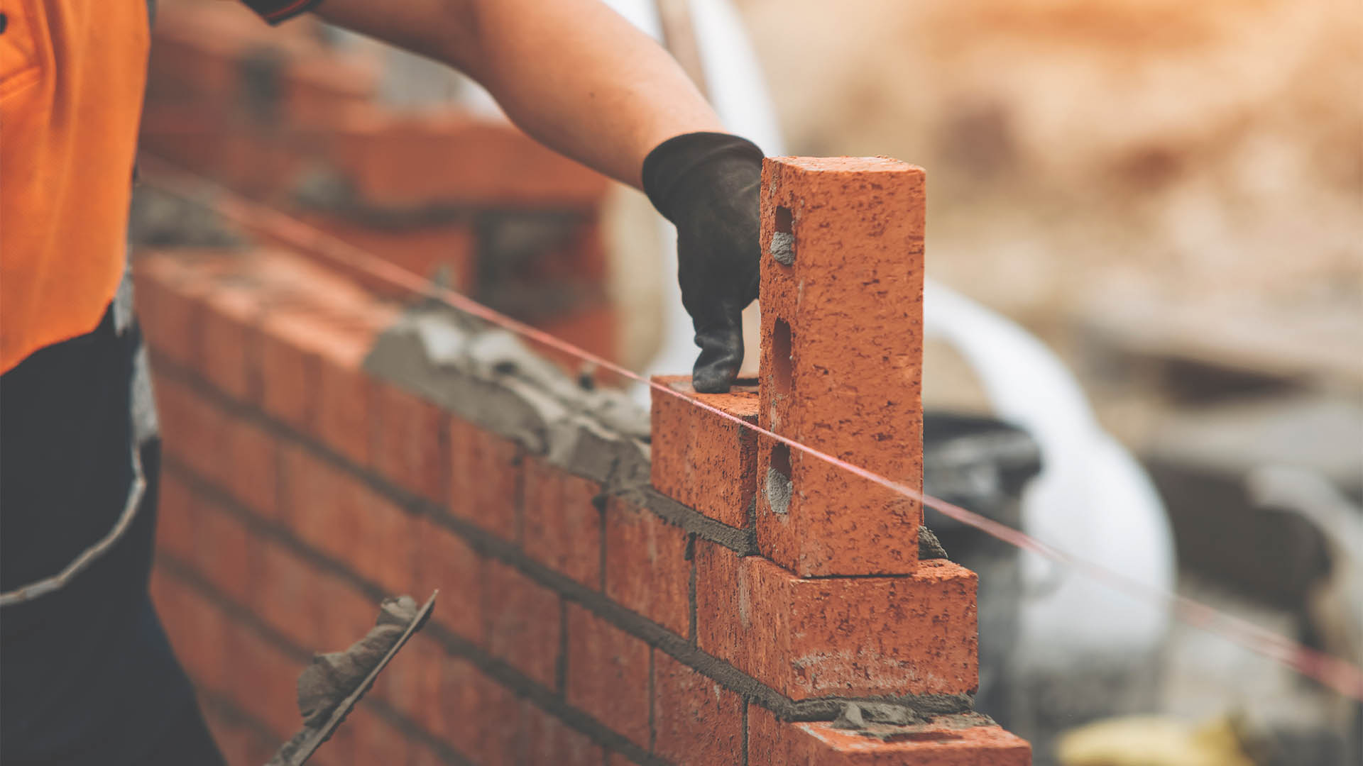 Construction Worker Placing Brick in Brick Wall During Daytime