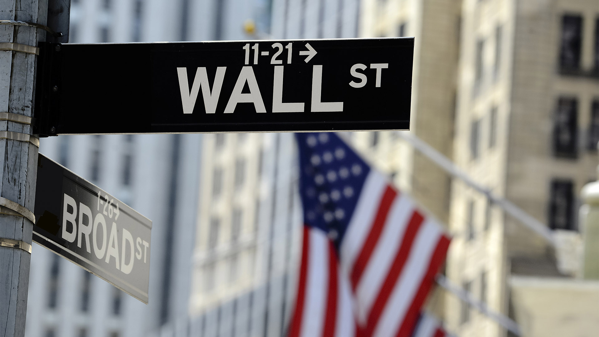 Wall street sign with focus on sign, blurred American flag background