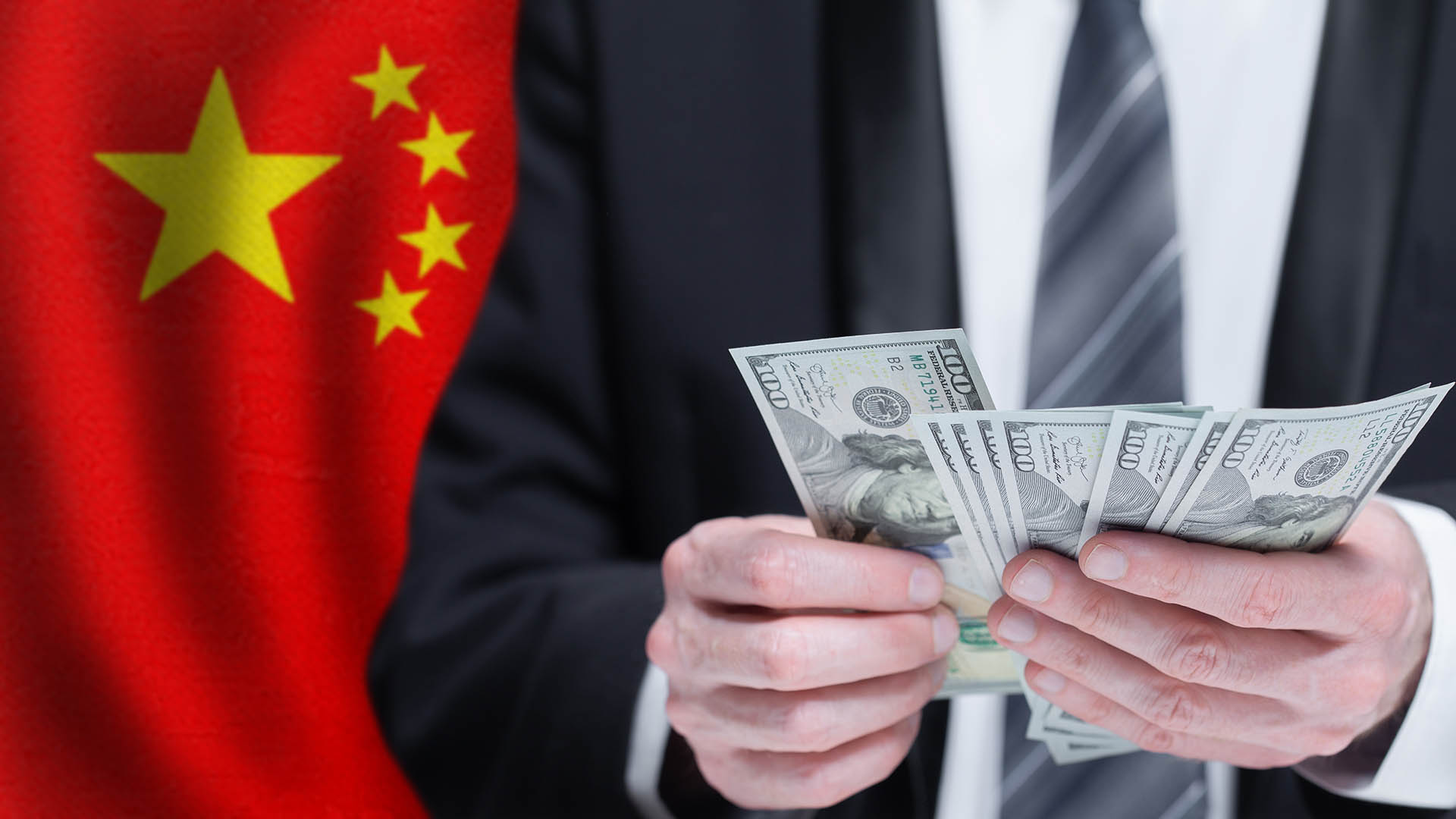 Hands holding dollar money on flag of China