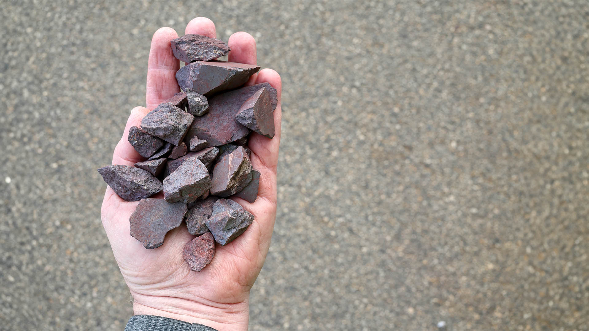 High grade (more than 63% Fe content) Australian iron ore, hematite (Fe2O3) held in hand. Blast furnaces feed for iron-making.