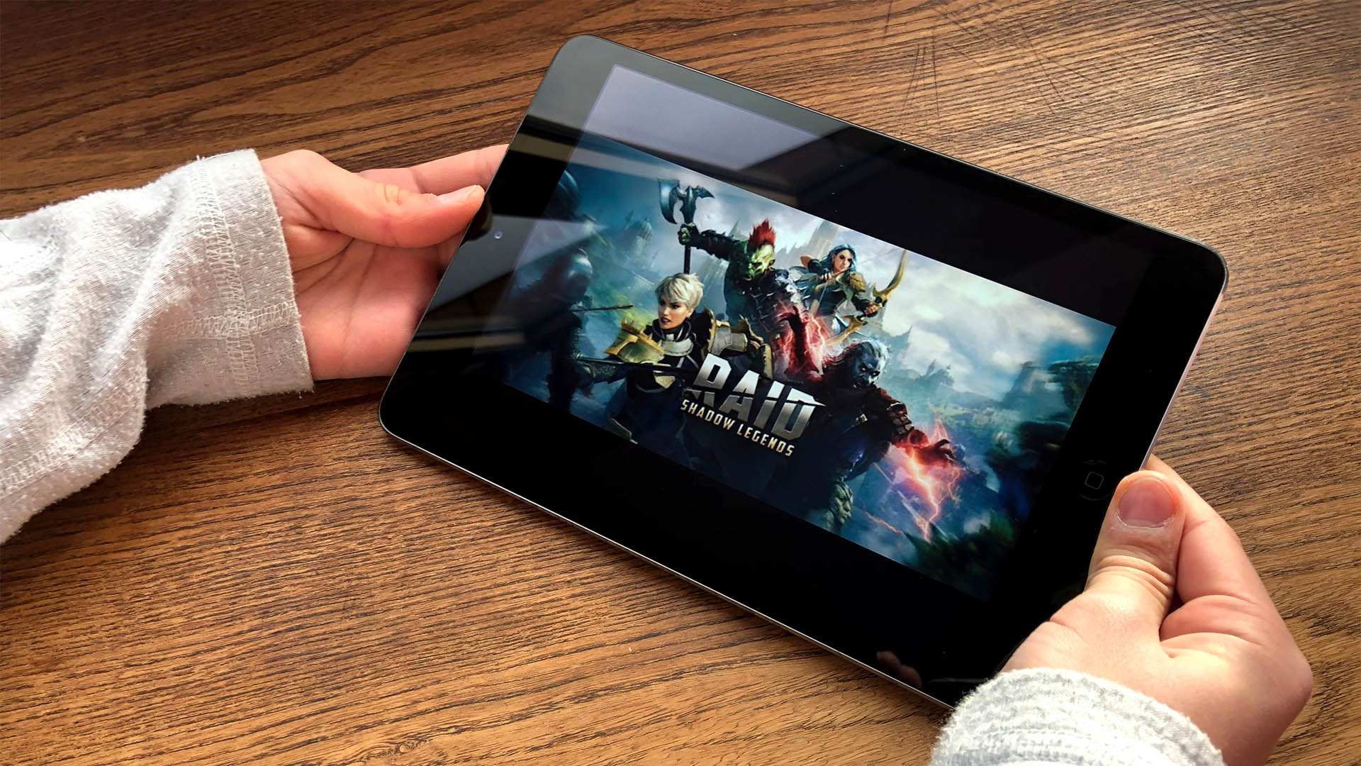 December 2019 Milan, Italy: Raid Shadow legends game application on tablet close-up on boy's hands.  Raid shadow Legends logo icon
