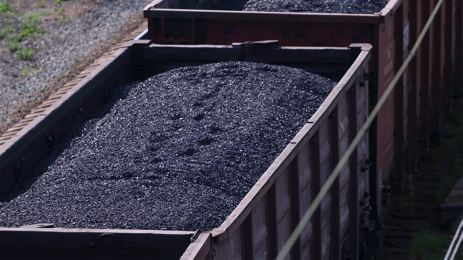 Close-up railroad tracks with wagons with coal on summer day