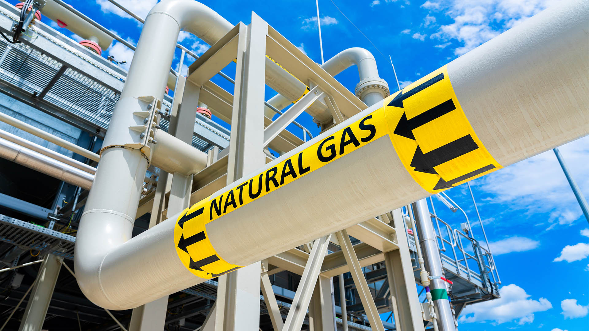 Natural gas pipeline with high pressure and direction sign at compressor station. Concept of energy transportation infrastructure
