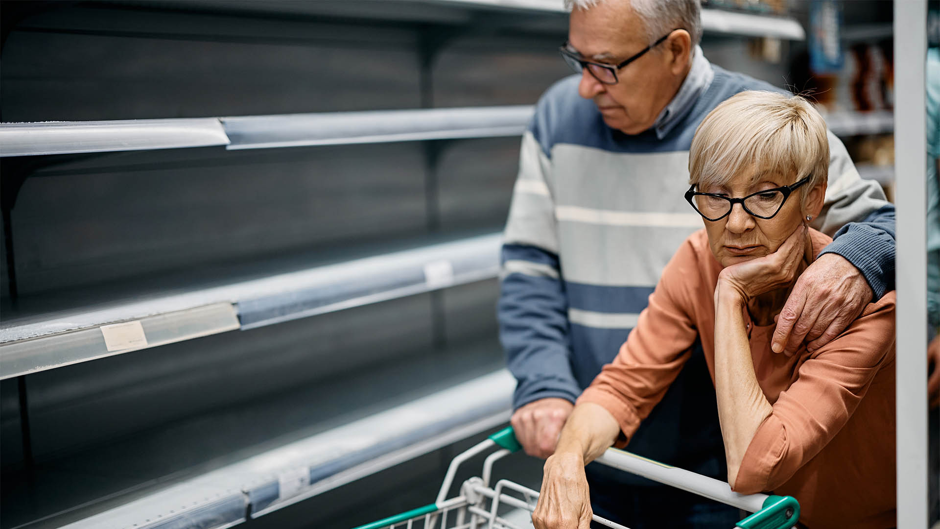 Senior woman and her husband feeling concerned about empty shelves and shortage of food in supermarket.