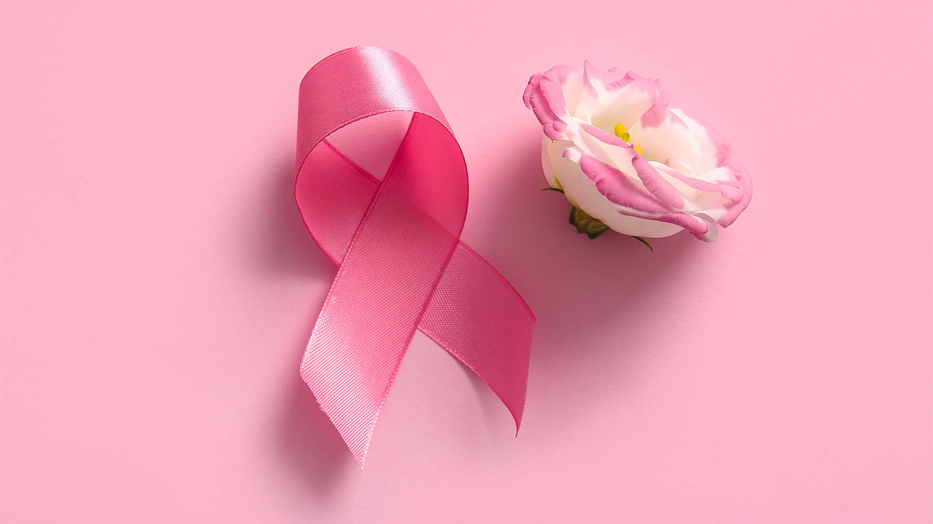Pink ribbon and flower on color background. Breast cancer awareness concept