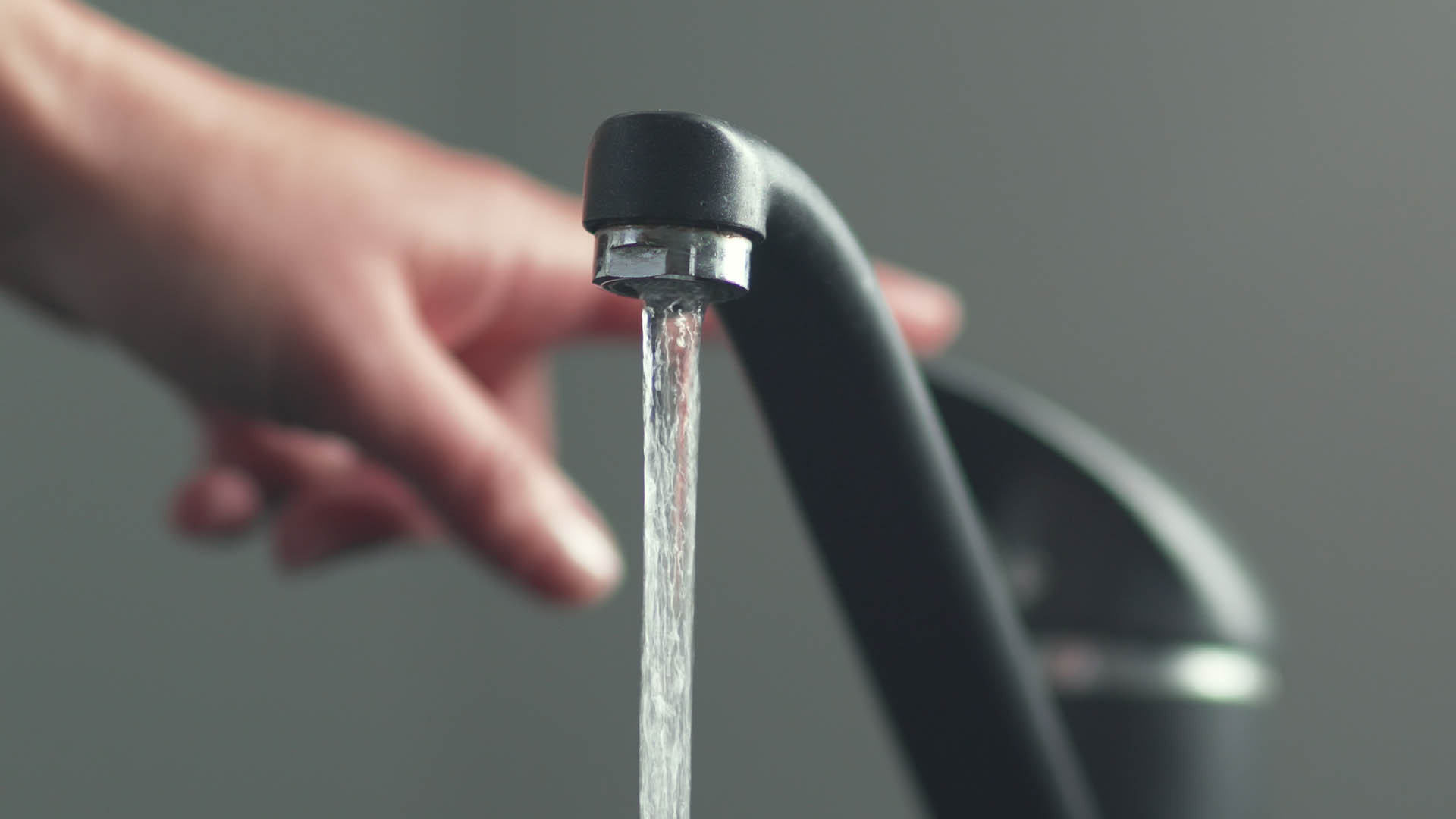 Woan is opening and closing water flow tap and filling sink with water. Water running from chrome faucet. Bathroom plumbing. Using water resources.